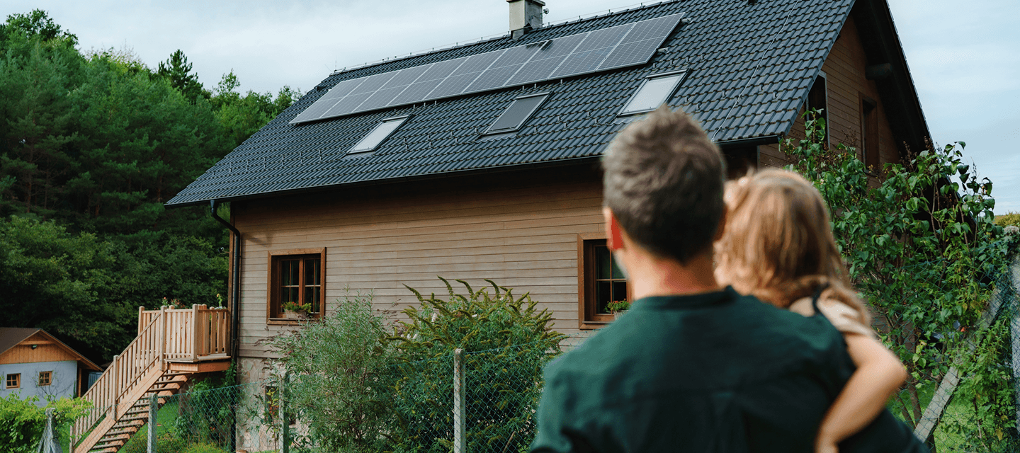 Maison équipée de panneaux solaires observée par une famille, illustration du secteur de l’assurance